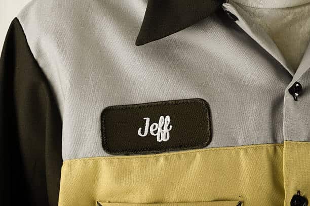 Work shirt with 'Jeff' embroidered in white on a dark patch on the left chest, showcasing a standard name tag size and placement.