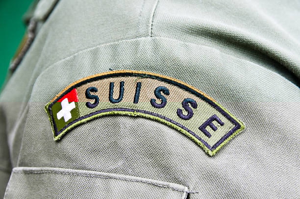 Close-up of a uniform shoulder with an embroidered 'Suisse' patch, featuring the Swiss flag, showcasing detailed stitching and placement.