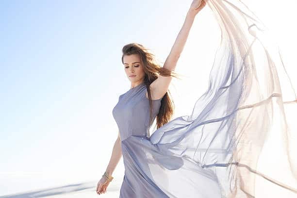 Woman in a flowing chiffon dress under sunlight, highlighting a lightweight synthetic cloth fabric type for apparel.
