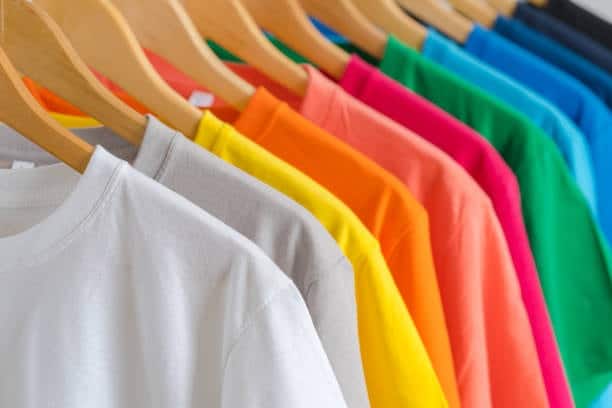 Row of colorful cotton t-shirts on hangers, showcasing a popular natural cloth fabric type for casual apparel.