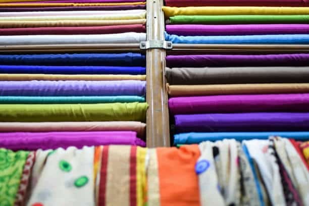 Display of colorful fabric rolls including silk and cotton, representing diverse cloth fabric types for textile apparel.