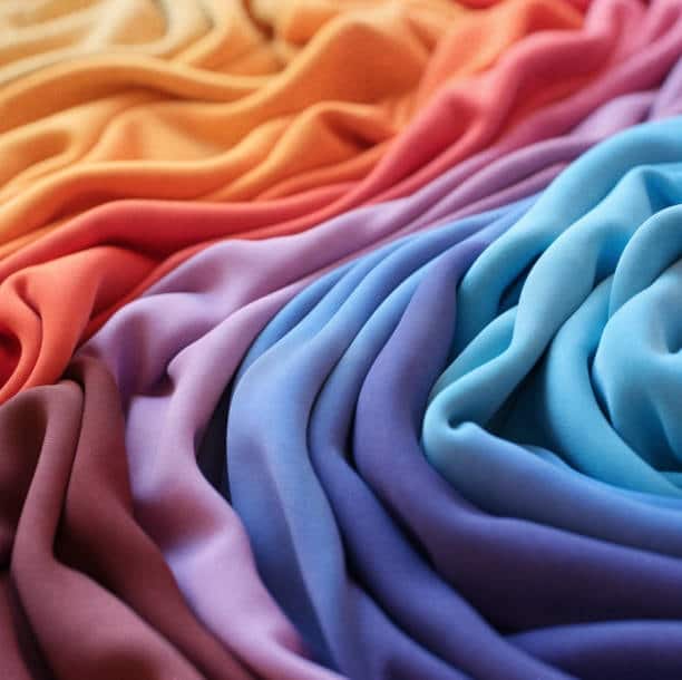Array of colorful silk fabrics, showcasing a luxurious natural cloth fabric type for elegant textile apparel.