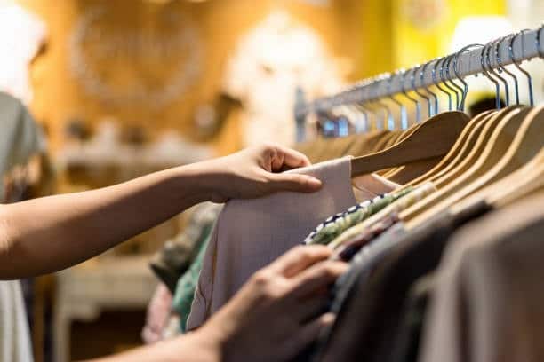 Person selecting fabric and garments in a clothing store.