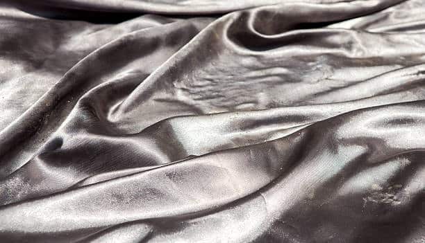 Close-up of shiny silver fabric with a soft, flowing texture.