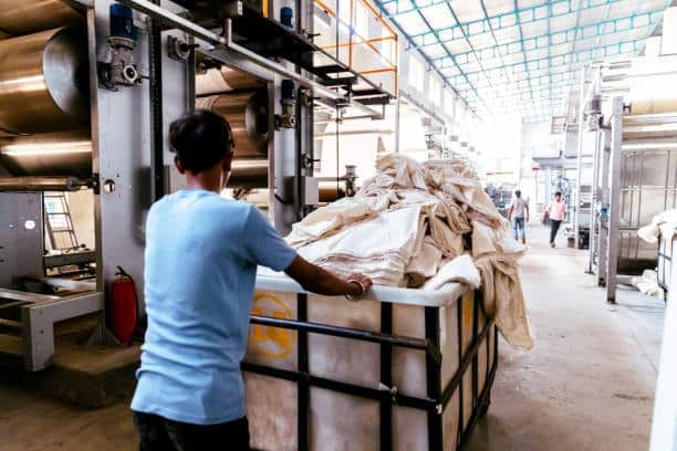 Worker handling raw fabric materials in a textile manufacturing factory.