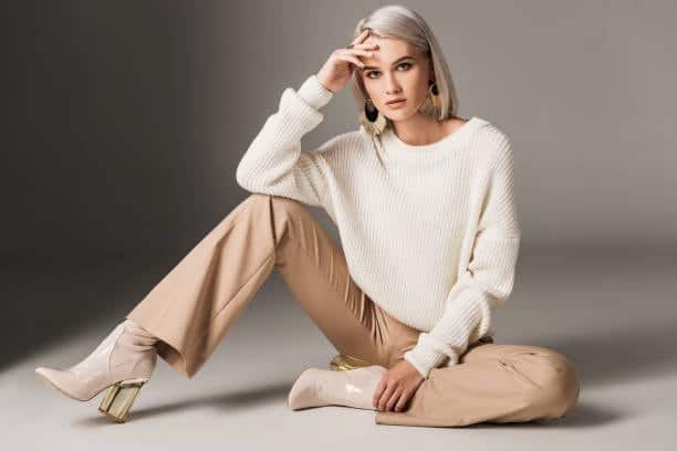 Person sitting in beige wide-leg pants, showcasing a style that requires more yards of fabric due to its voluminous design.