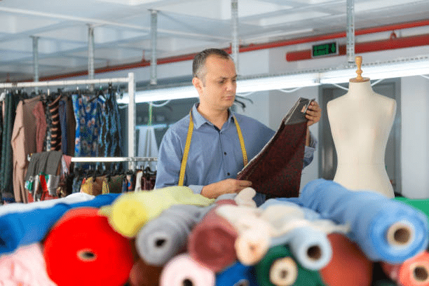 Designer selecting fabric from textile rolls for fashion production