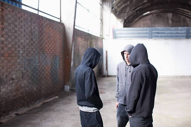 Group of young men in dark hoodies standing in an industrial space, emphasizing streetwear and urban hoodie appeal
