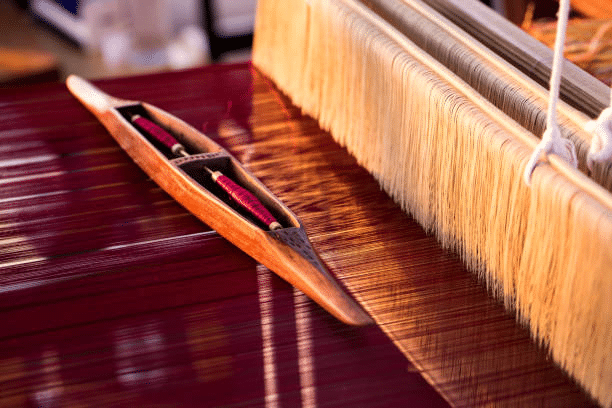 Handloom weaving process using shuttle and threads in garment production